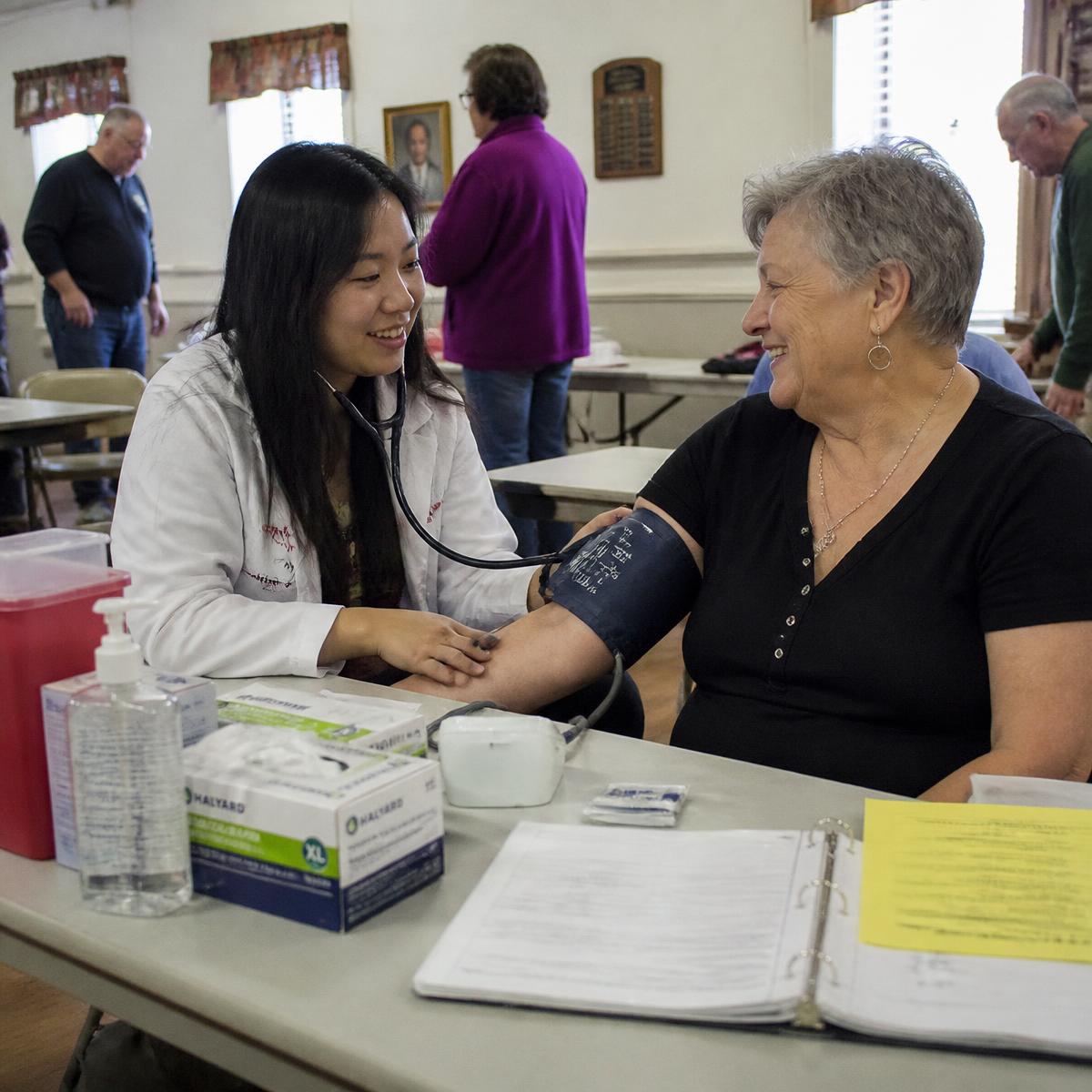 Anchor pharmacist reviewing a resident's medications in a comfortable clubhouse lounge